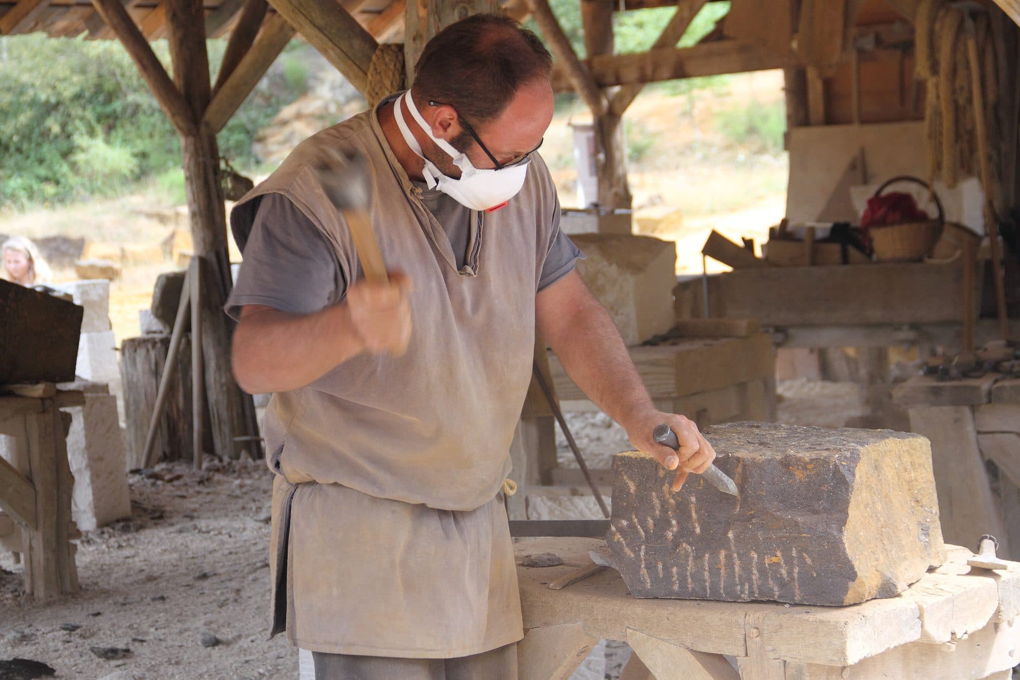 Stonemason dressing a block of stone with a chisel