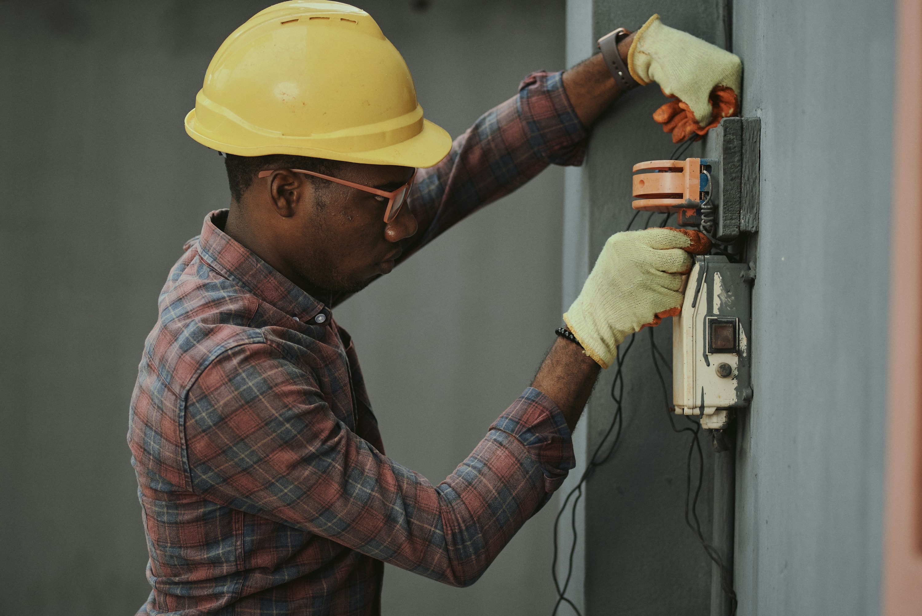 An electrician working at a home panel, tools in hand.
