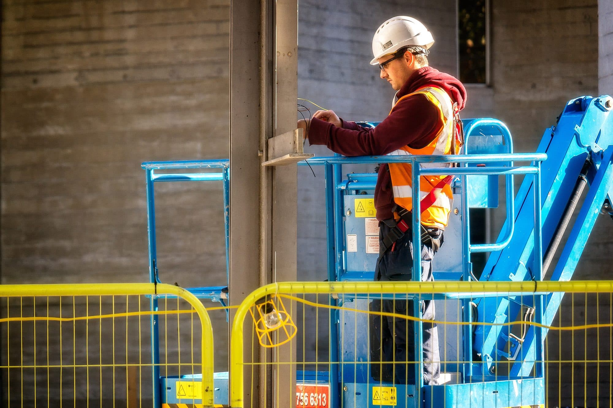 Electrician working from a lift on a commercial wall